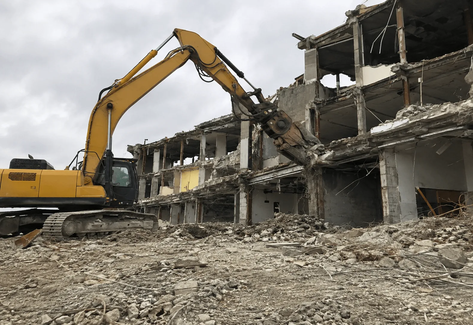 Large excavator with a demolition attachment working a multi-story masonry building