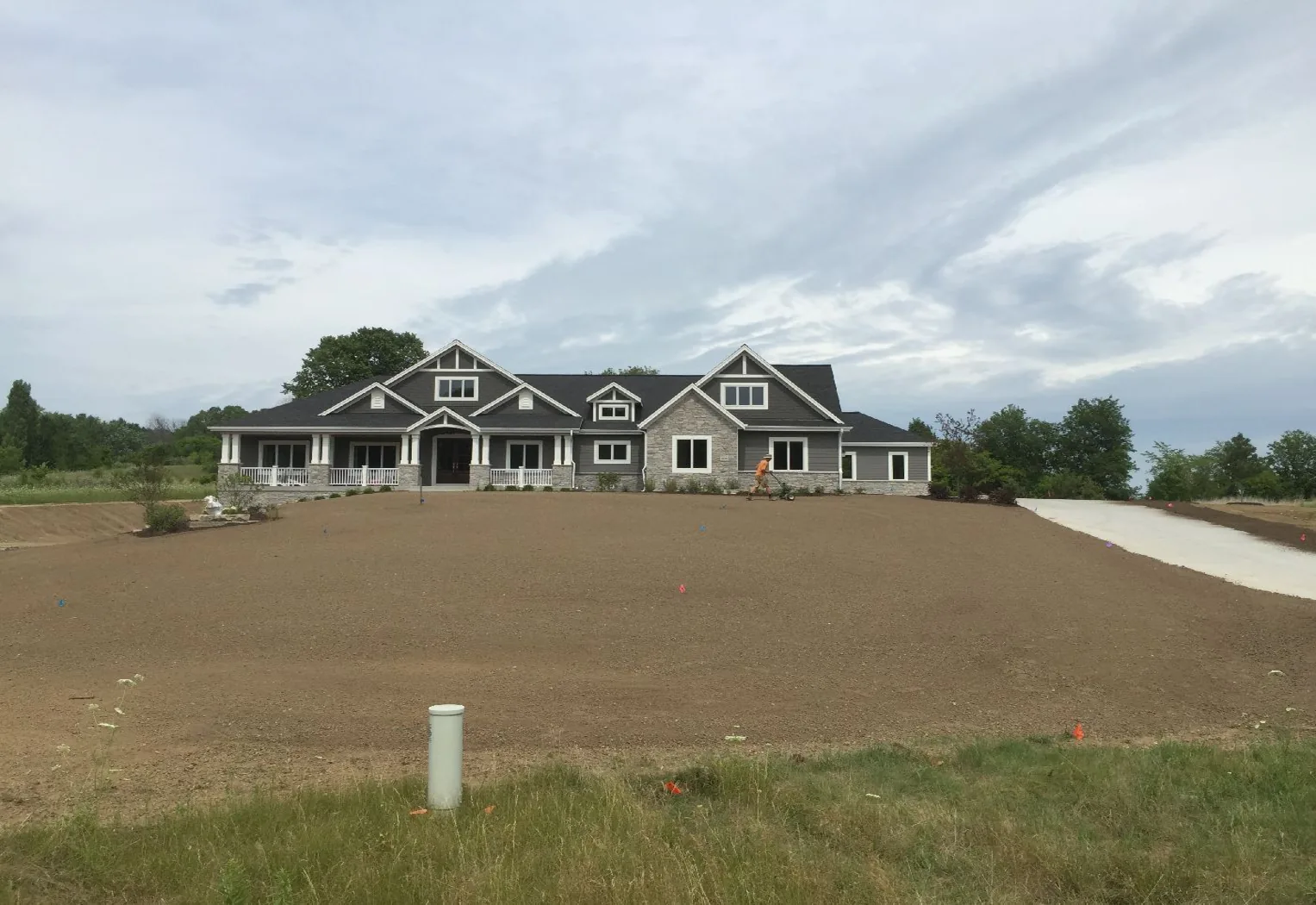 Freshly graded dirt yard sloping away from a newly built shingled house
