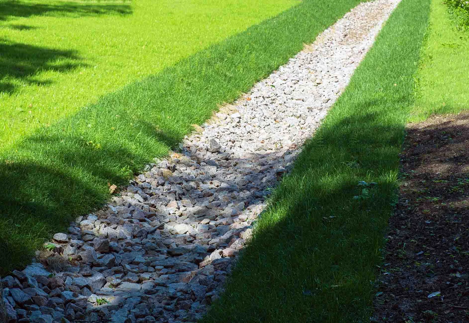 Stone-filled trench line running across a mown lawn